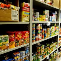 Shelves stocked with canned food items in a community food pantry.